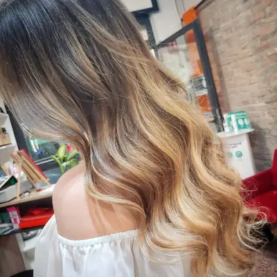 Degradè dal castano al biondo caldo su capelli lunghi ondulati